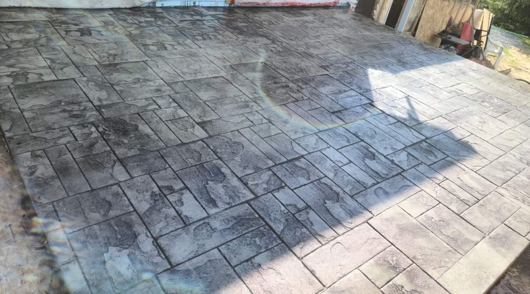 Une allée en béton avec un motif de briques et une ombre dessus.