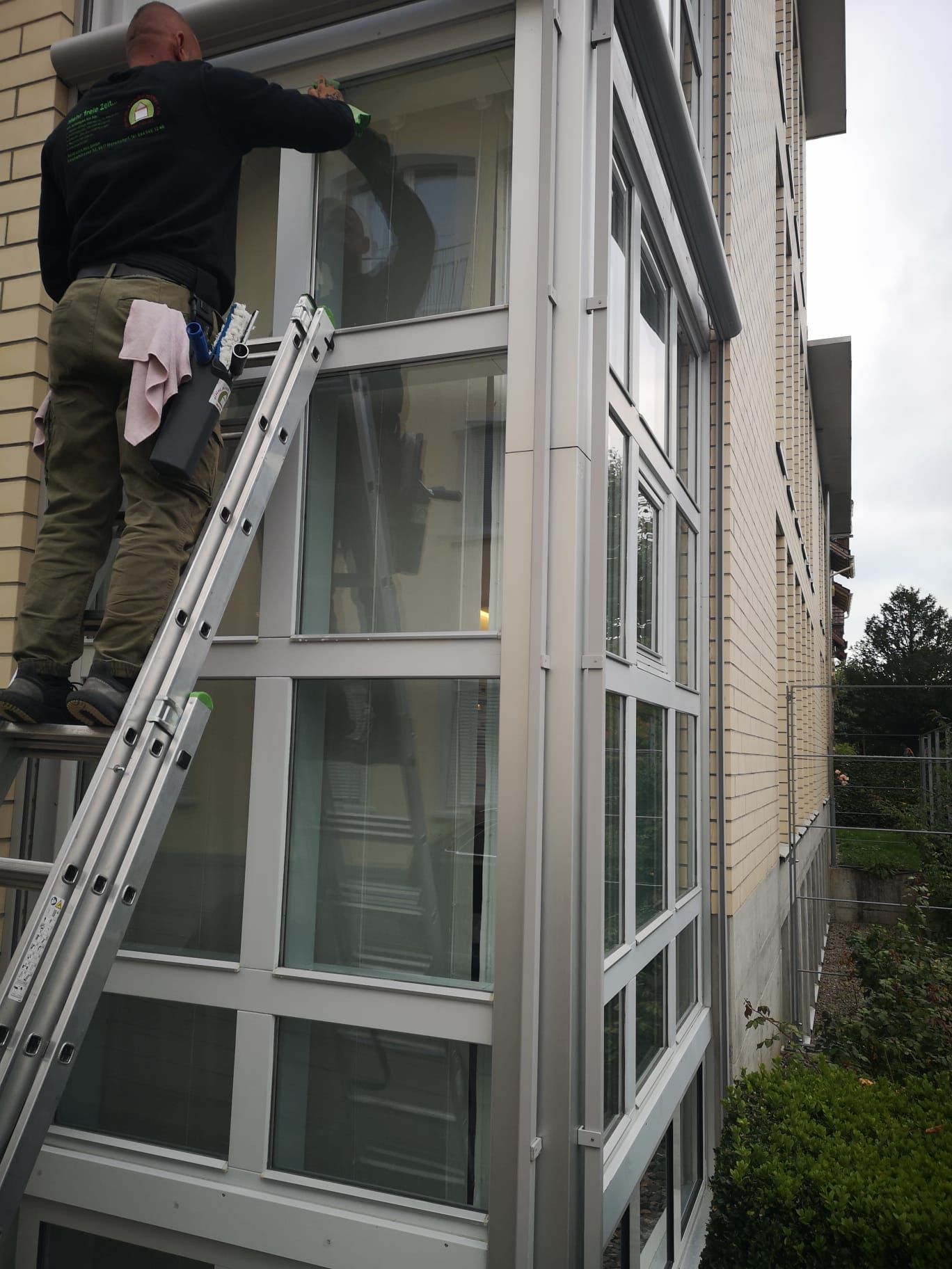 Mann bei der Fensterreinigung Gebäude