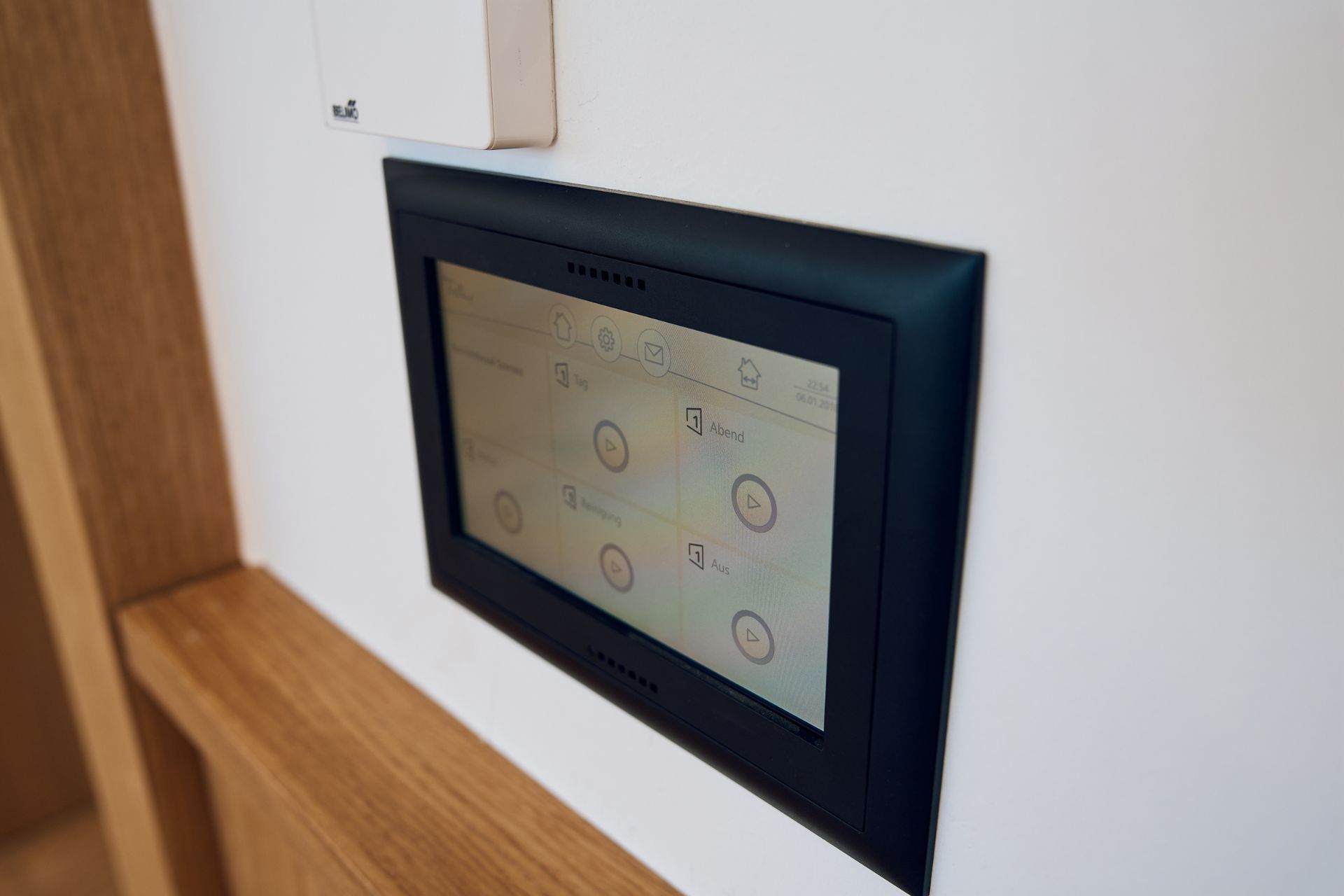 An einer weißen Wand ist ein schwarzer Thermostat angebracht.