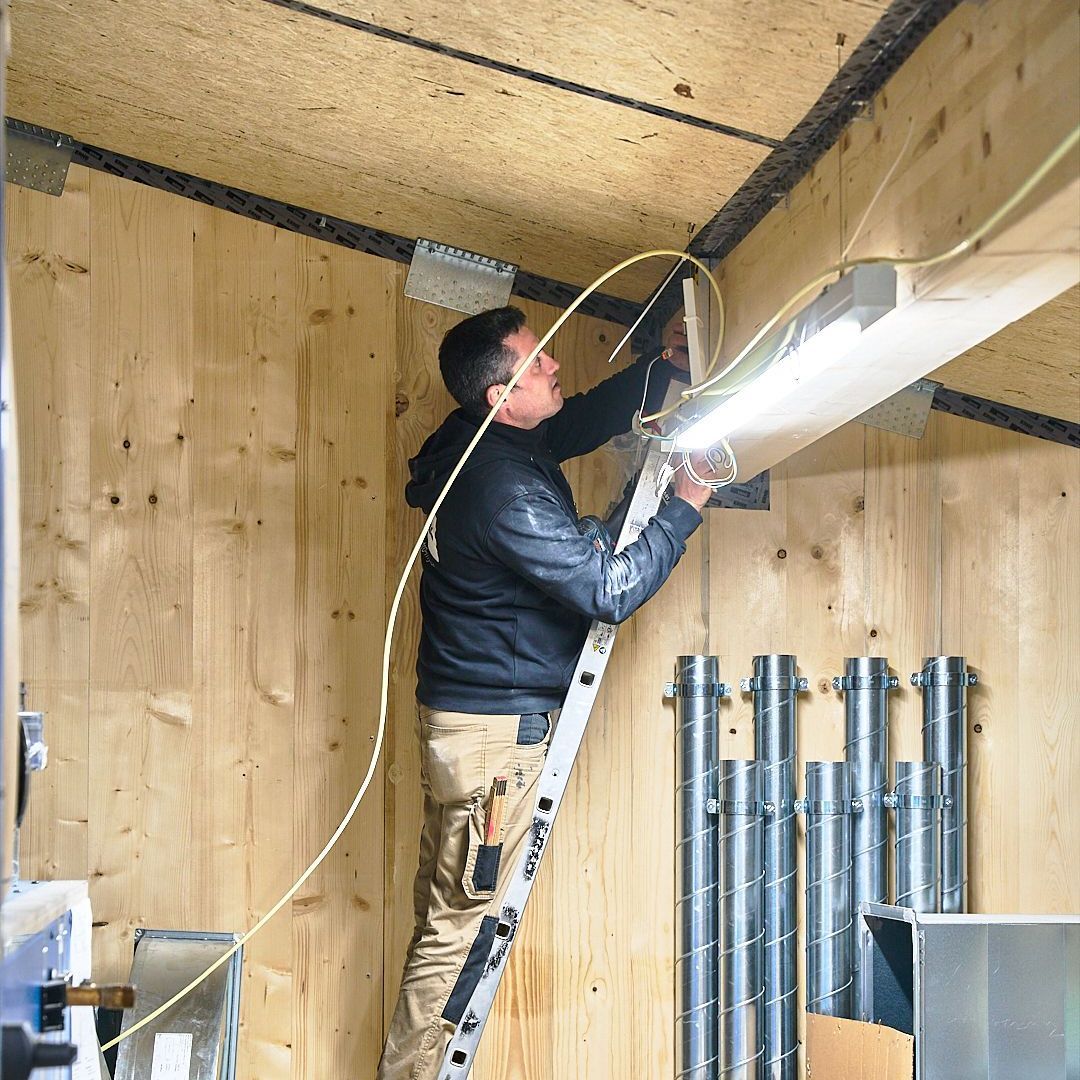 Ein Mann auf einer Leiter, der an einer Leuchte arbeitet