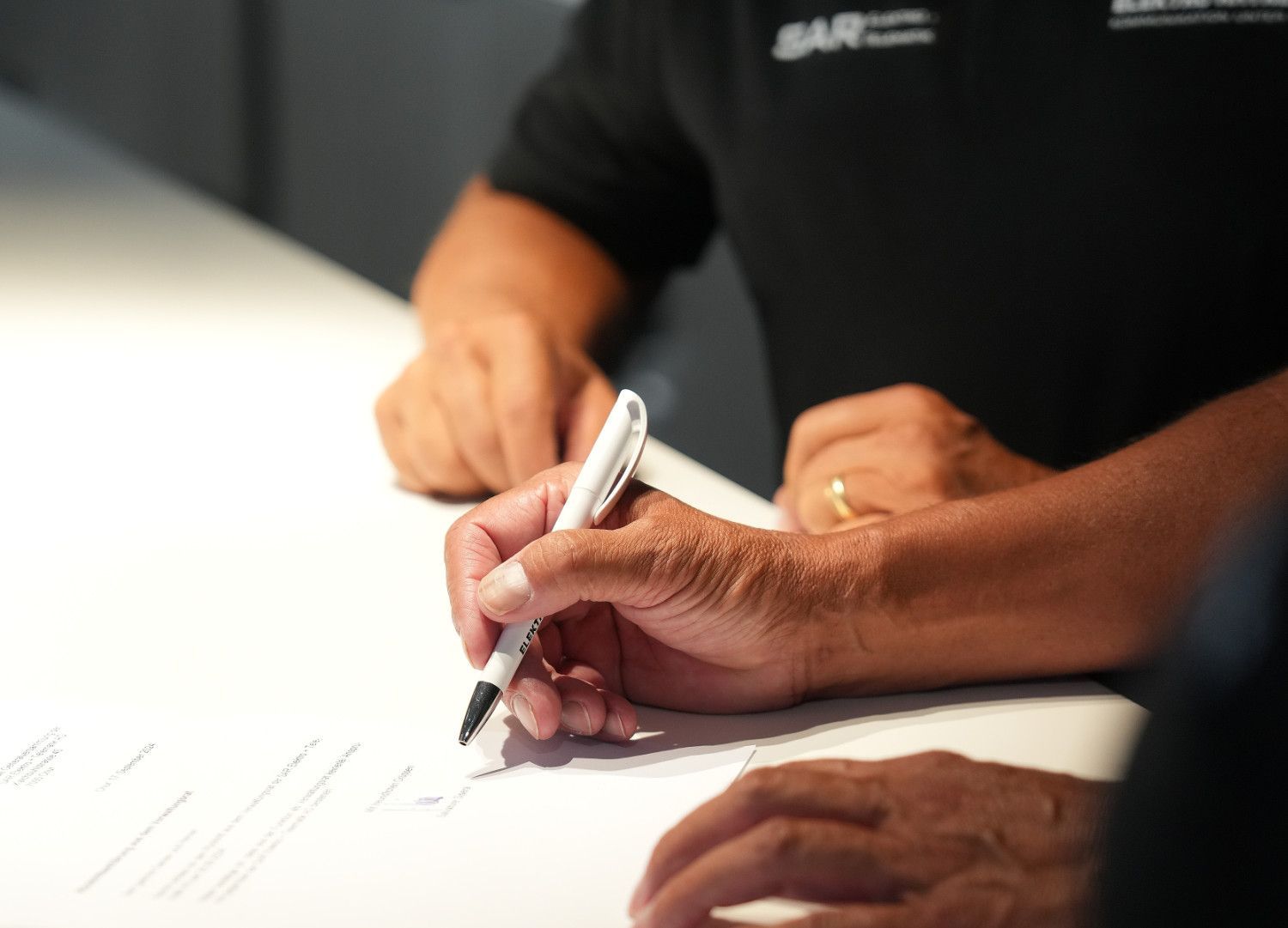 Eine Person schreibt mit einem Stift auf ein Blatt Papier.