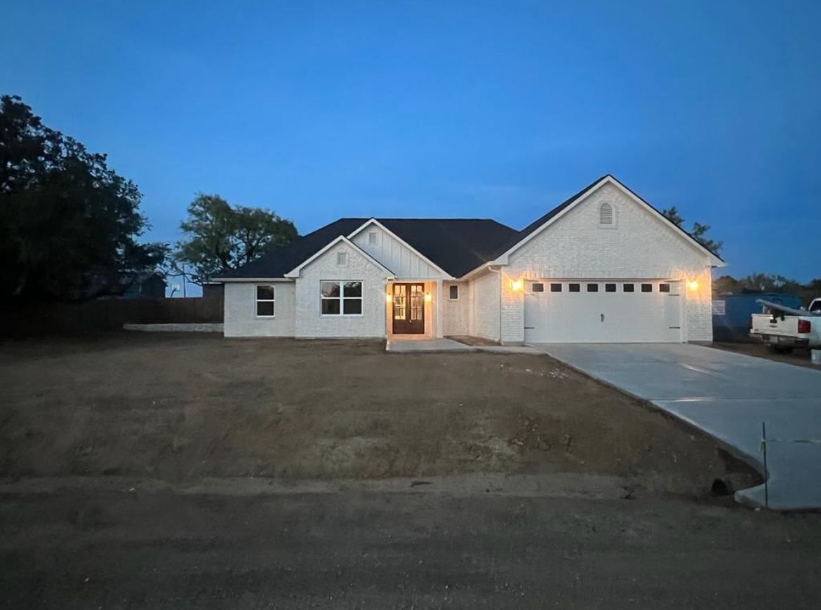 A white house with a black roof is lit up at night.