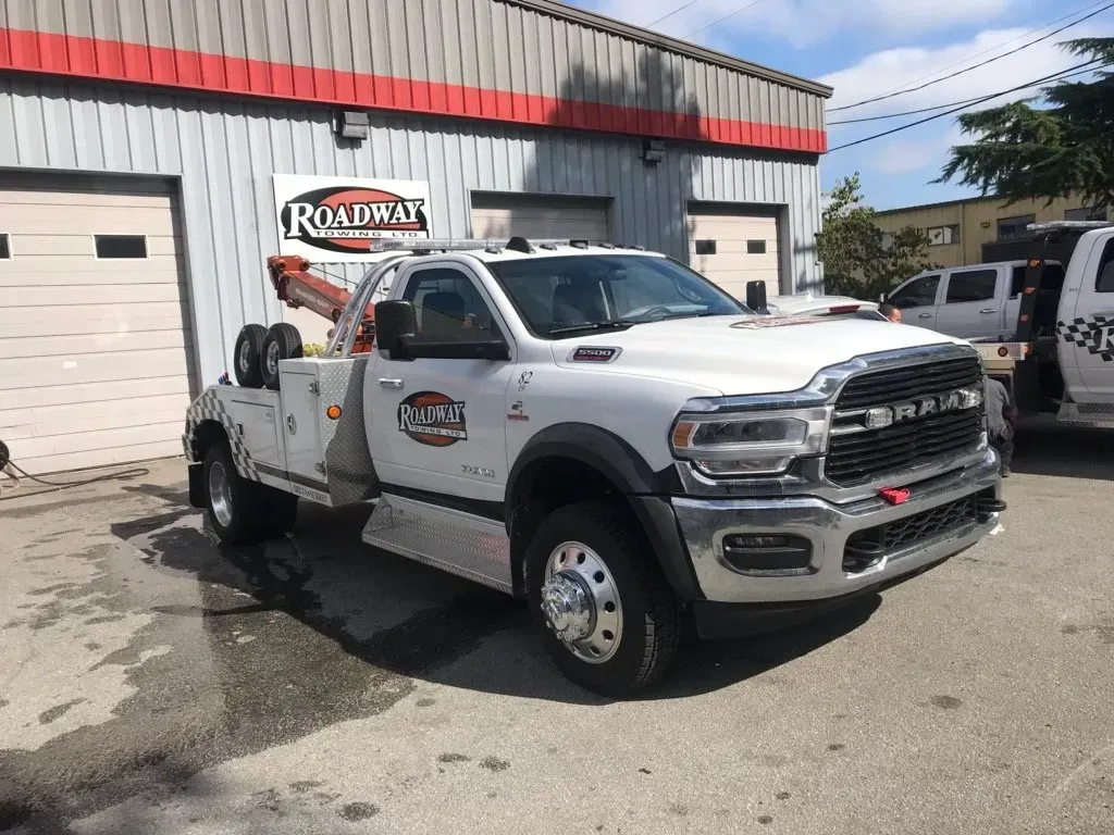 A white Ram commercial tow truck parked in front of a building with a 