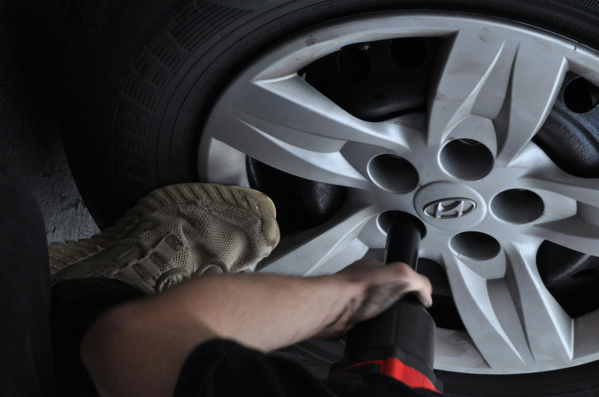 A person uses an impact wrench to tighten a lug nut on a Hyundai car wheel.