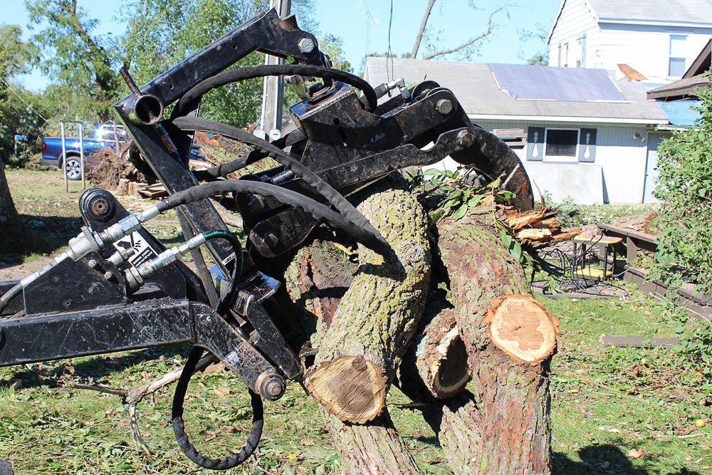 A large tree stump is being lifted by a hydraulic crane.