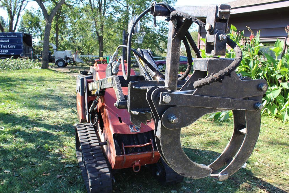 A tractor with a large claw attached to it is parked in a grassy field.