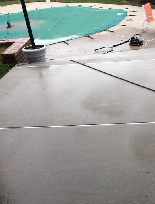 A concrete patio with a swimming pool in the background