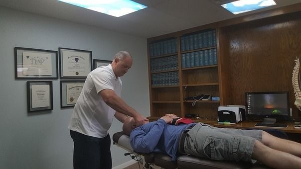 Chiropractor adjusting a patient on a treatment table in a clinic office