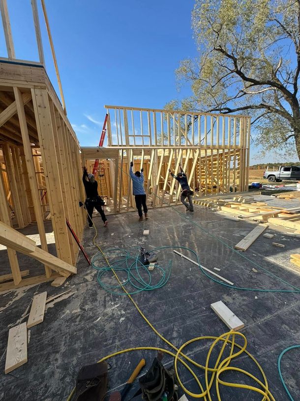 A group of construction workers are working on a house under construction.