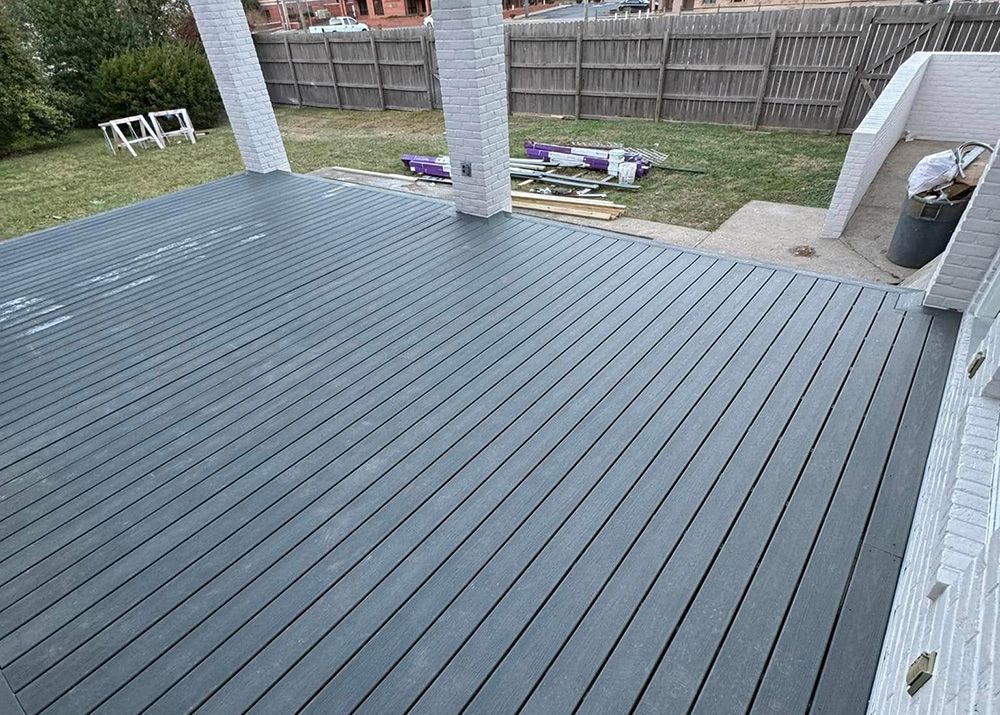 A gray deck with a white fence in the background.