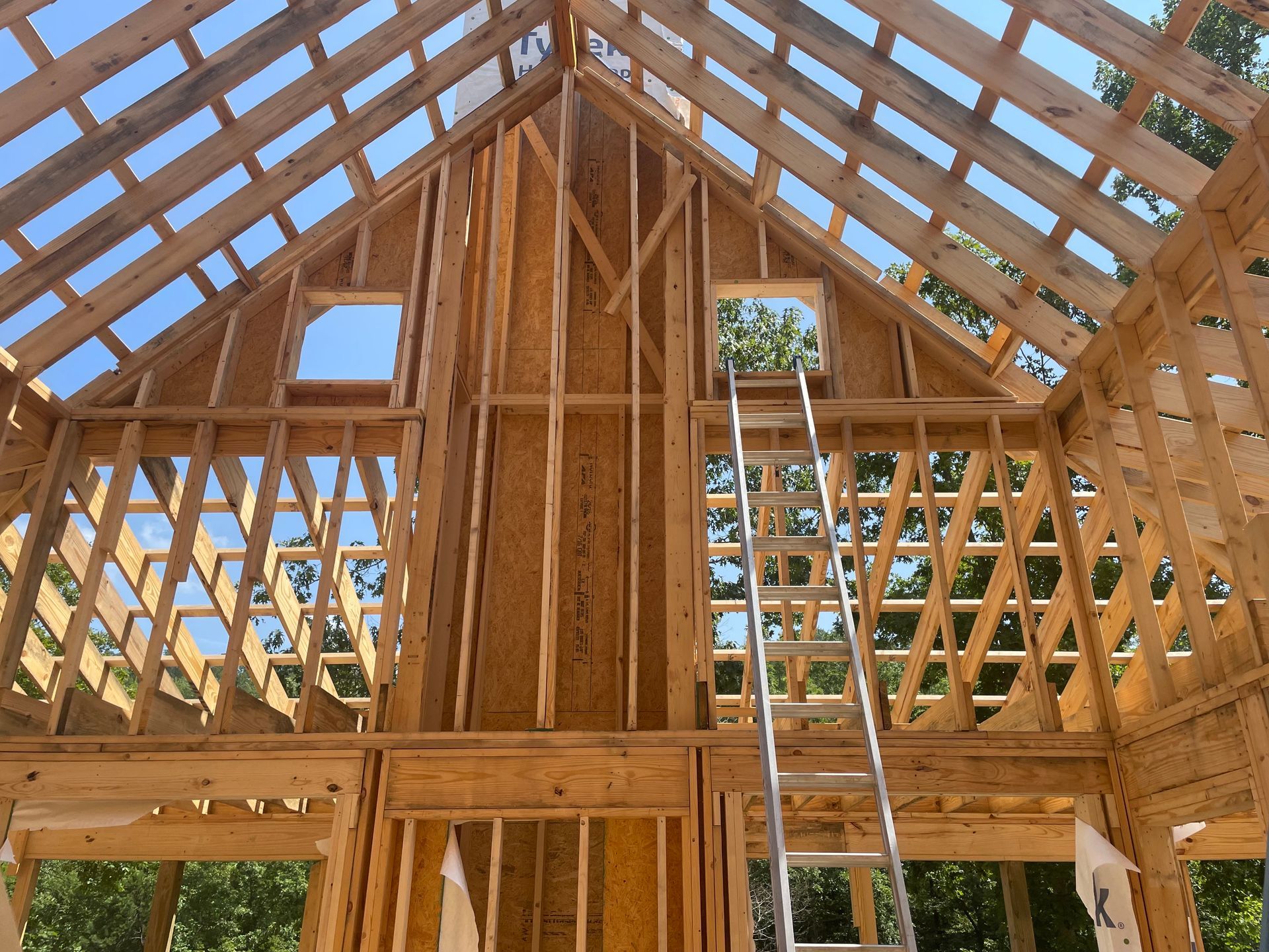 The inside of a wooden house under construction with a ladder.