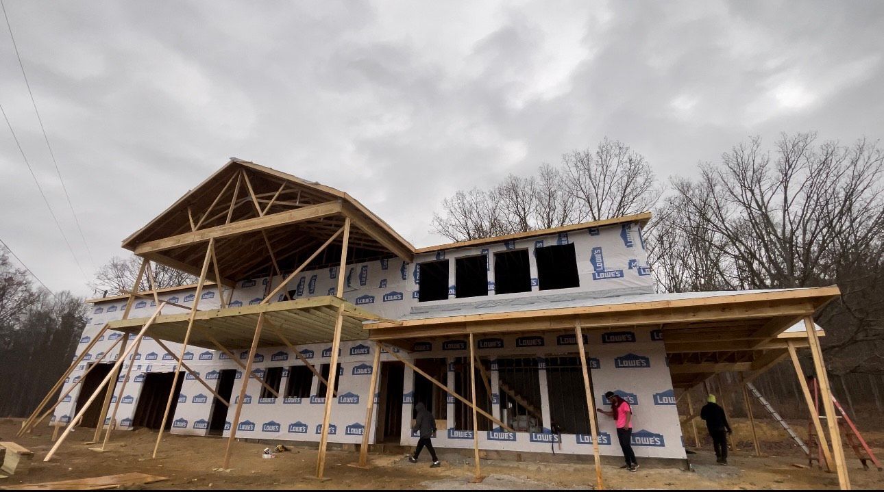 A large house is being built in the middle of a field.