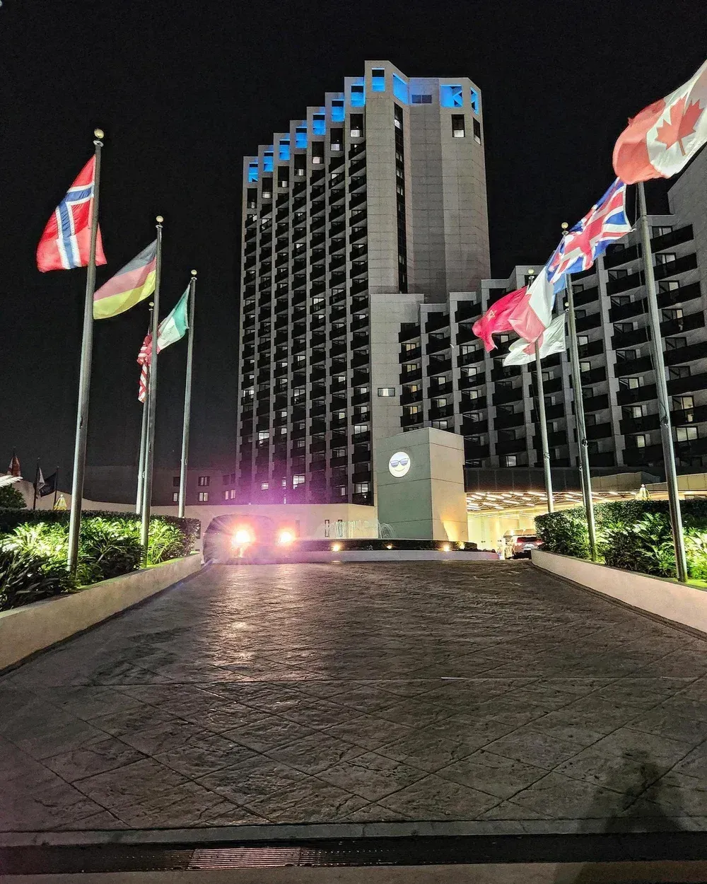 Hotel at night with flags of various countries and a lit entrance.