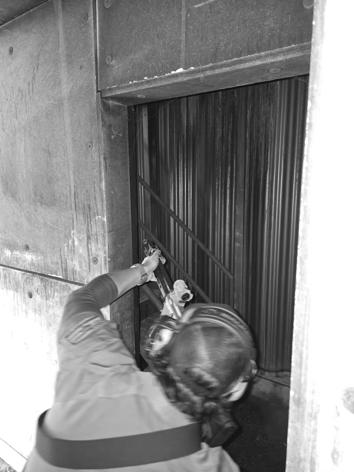 Person reaching into a dark opening with metal rods, possibly for a maintenance or repair task.