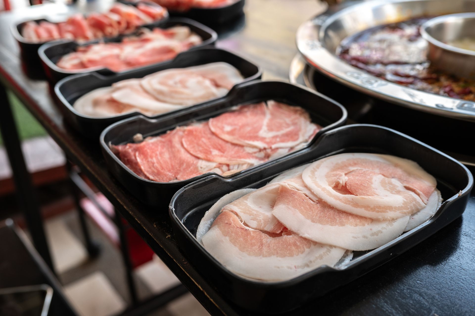 A table topped with trays of meat and vegetables.