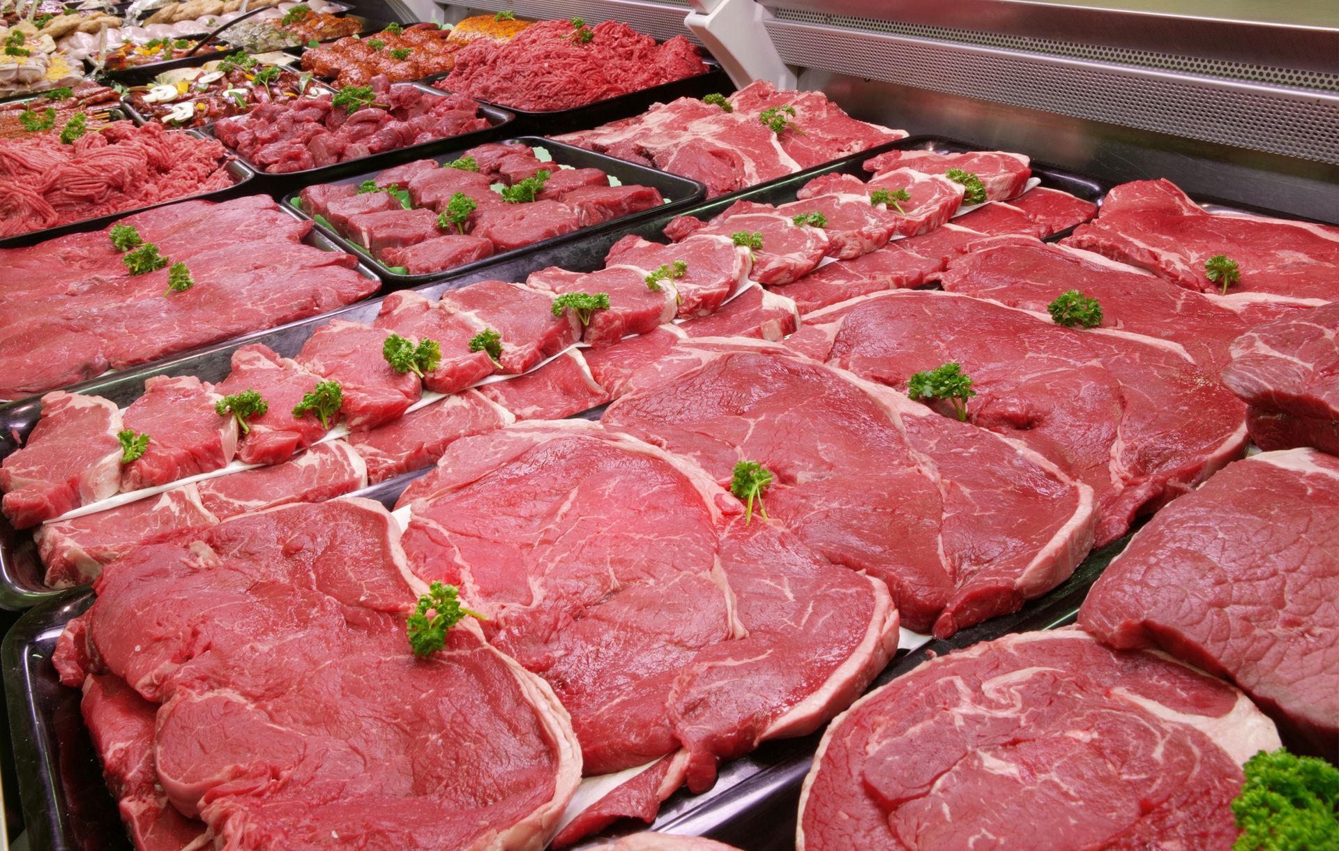 There are many different types of meat on display in a butcher shop.