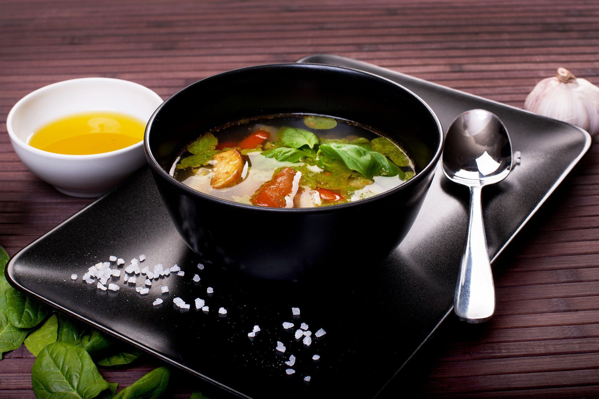 A bowl of soup with a spoon on a black plate