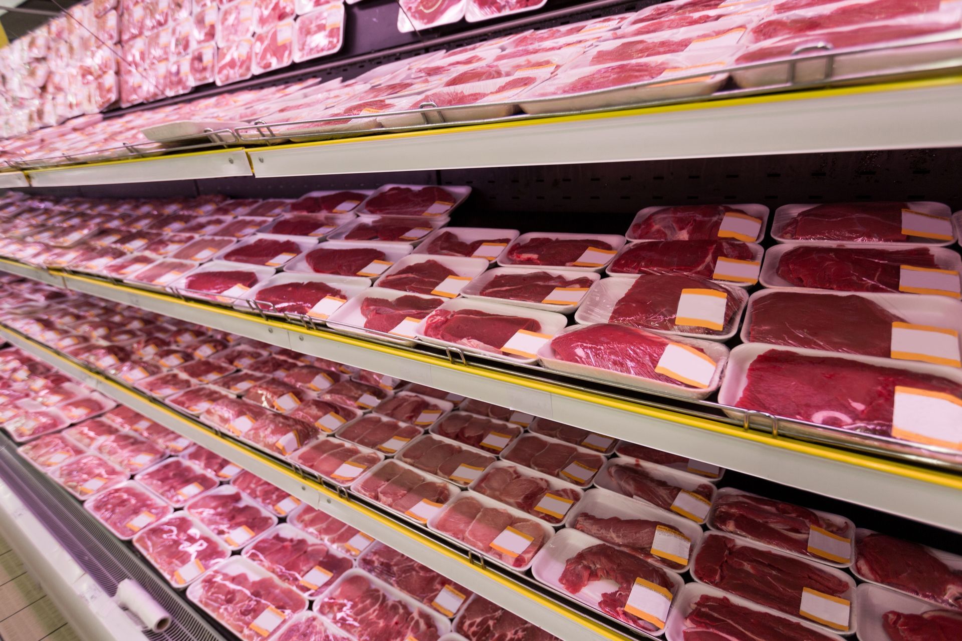 A grocery store aisle filled with lots of meat in plastic trays.