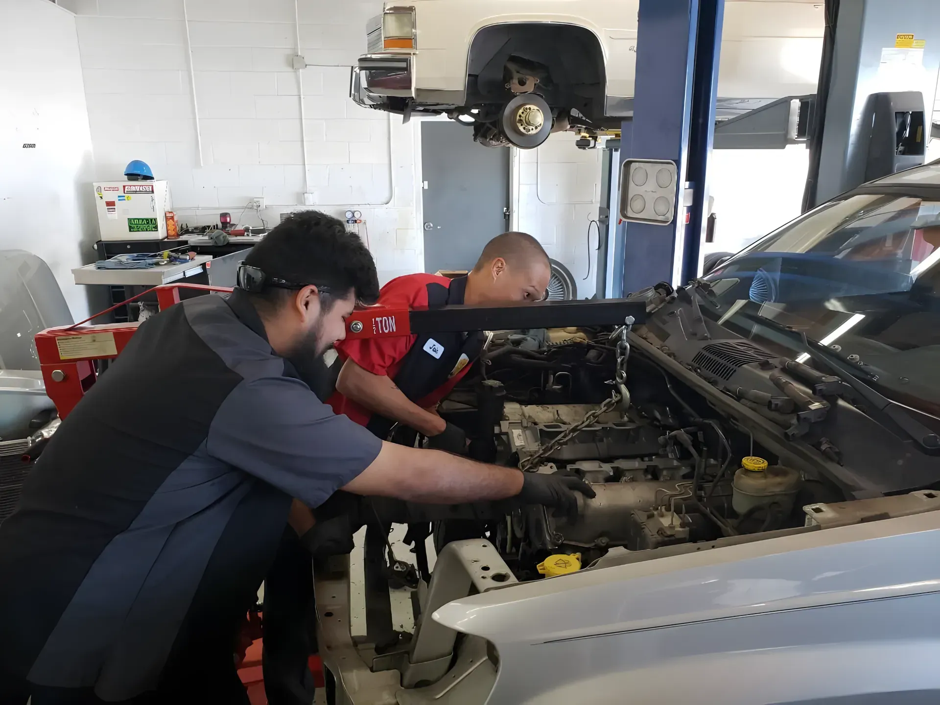 Two men are working on a car engine in a garage. | Friendly Auto Centers