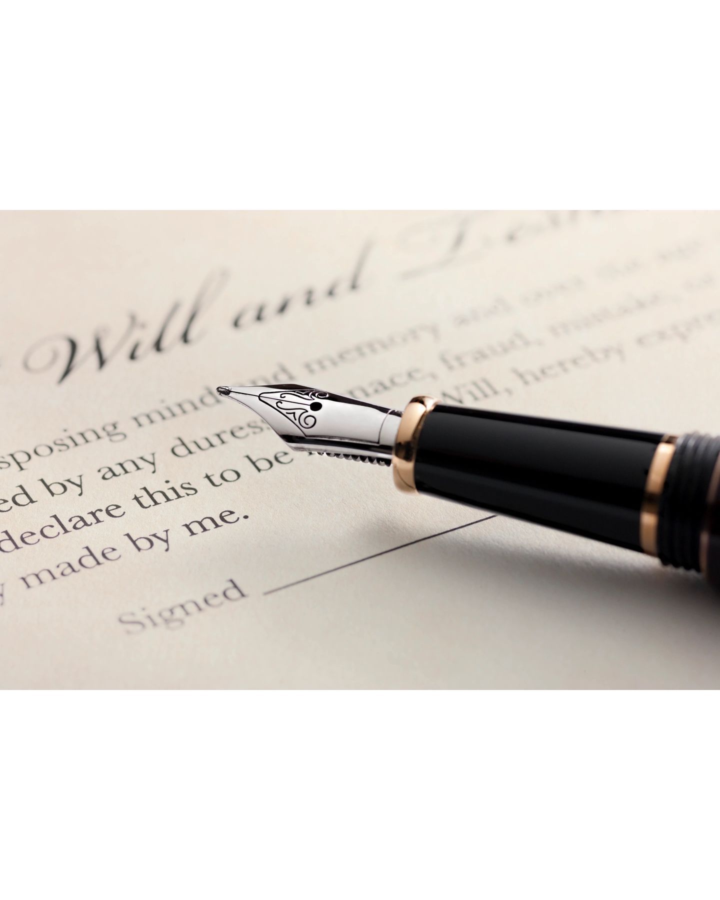 A fountain pen is laying on top of a will and testament