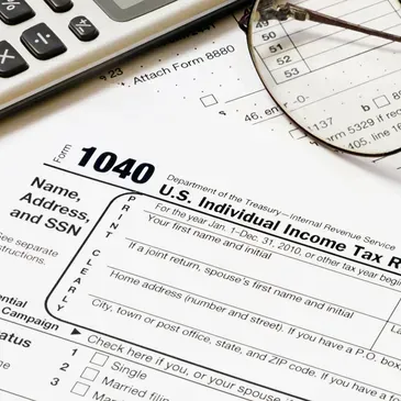 A 1040 form with a calculator and glasses on top of it