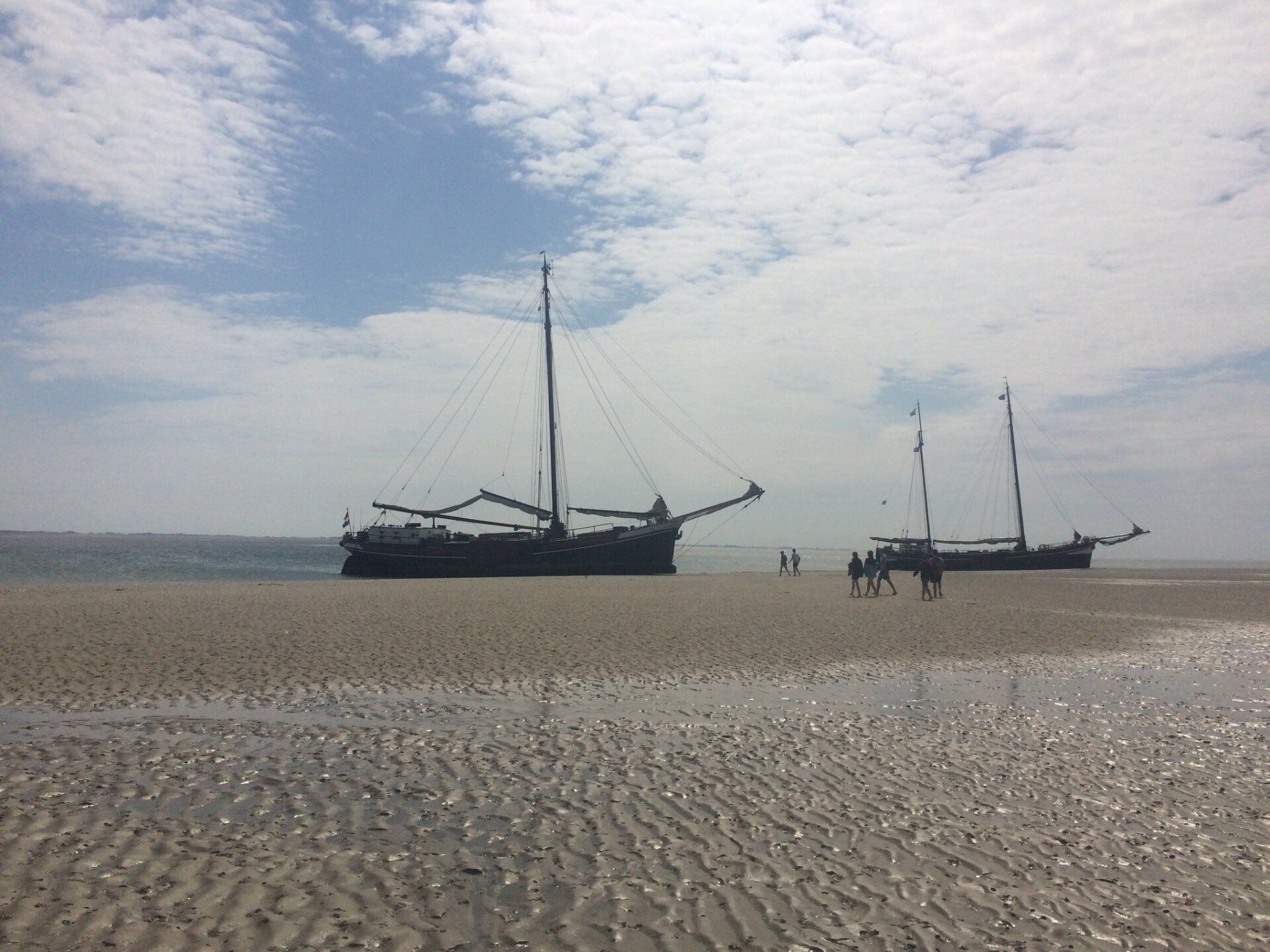 Zwei Segelboote strandeten unter einem bewölkten Himmel an einem Sandstrand.