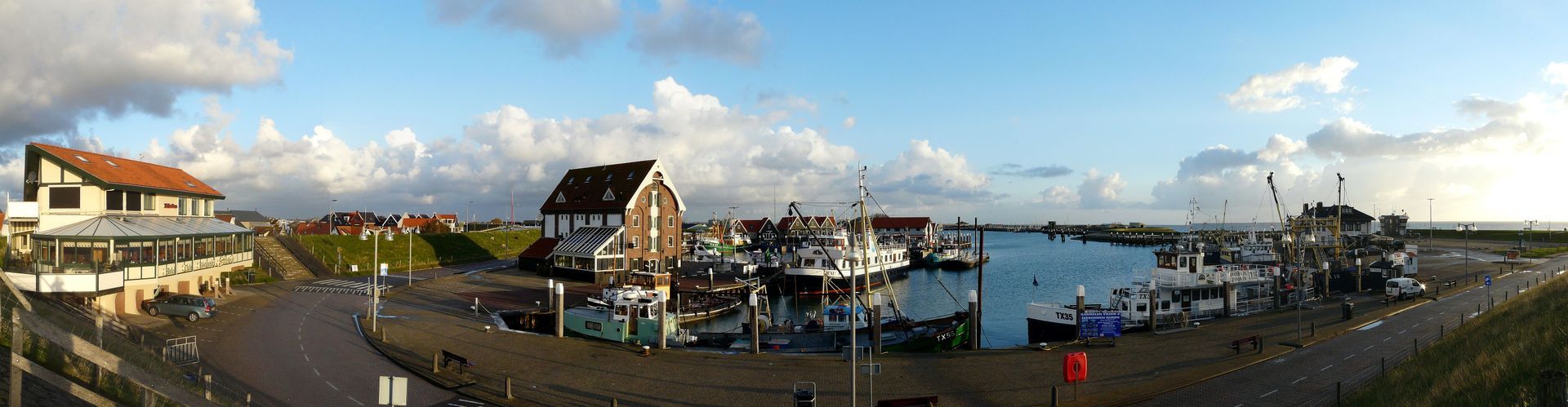 Panorama eines Hafens mit Booten, Gebäuden und bewölktem Himmel. es geht um die Hafen von Oudeschild auf Texel