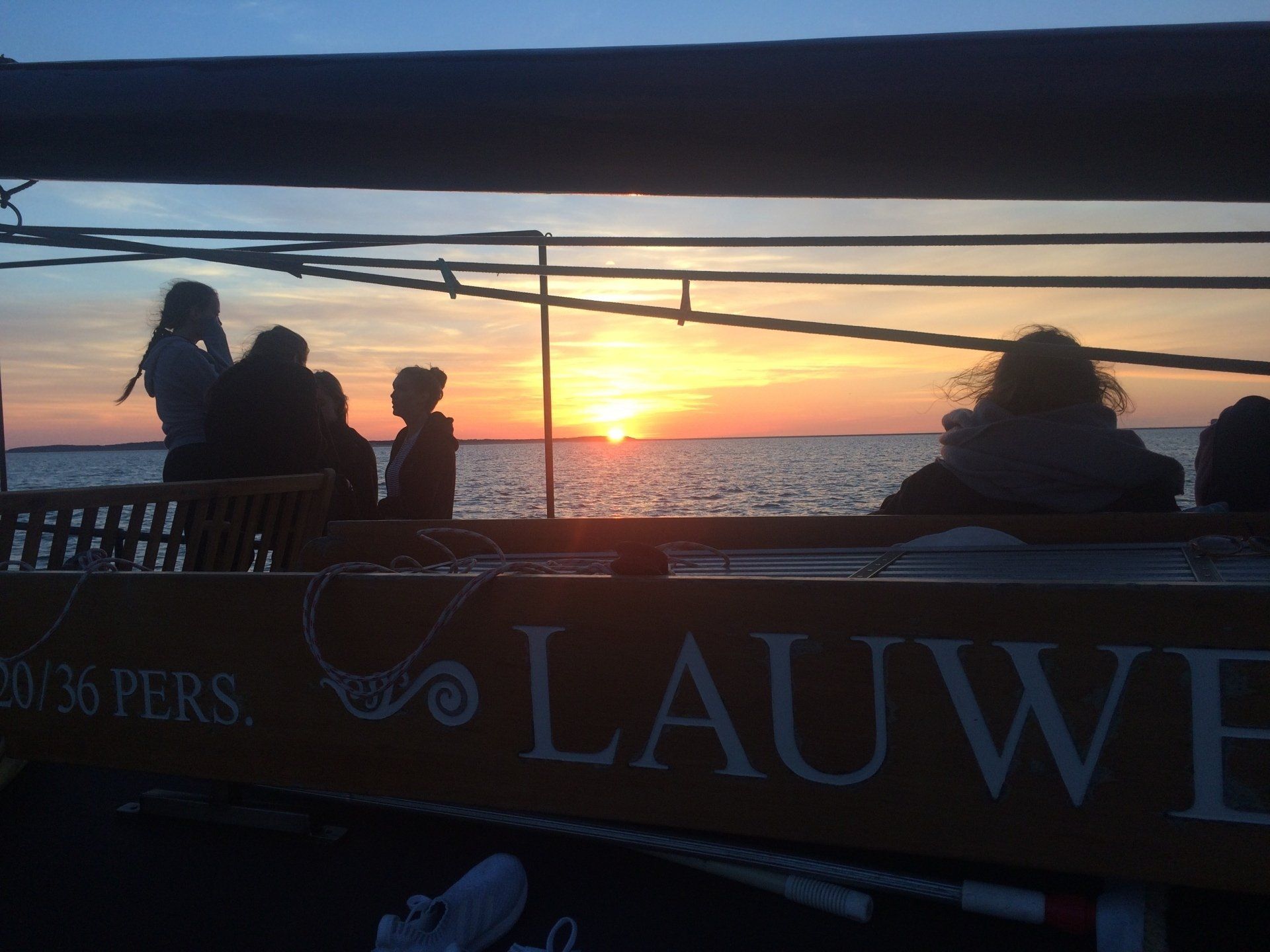 Menschen auf einem Boot beobachten einen Sonnenuntergang über dem Meer.