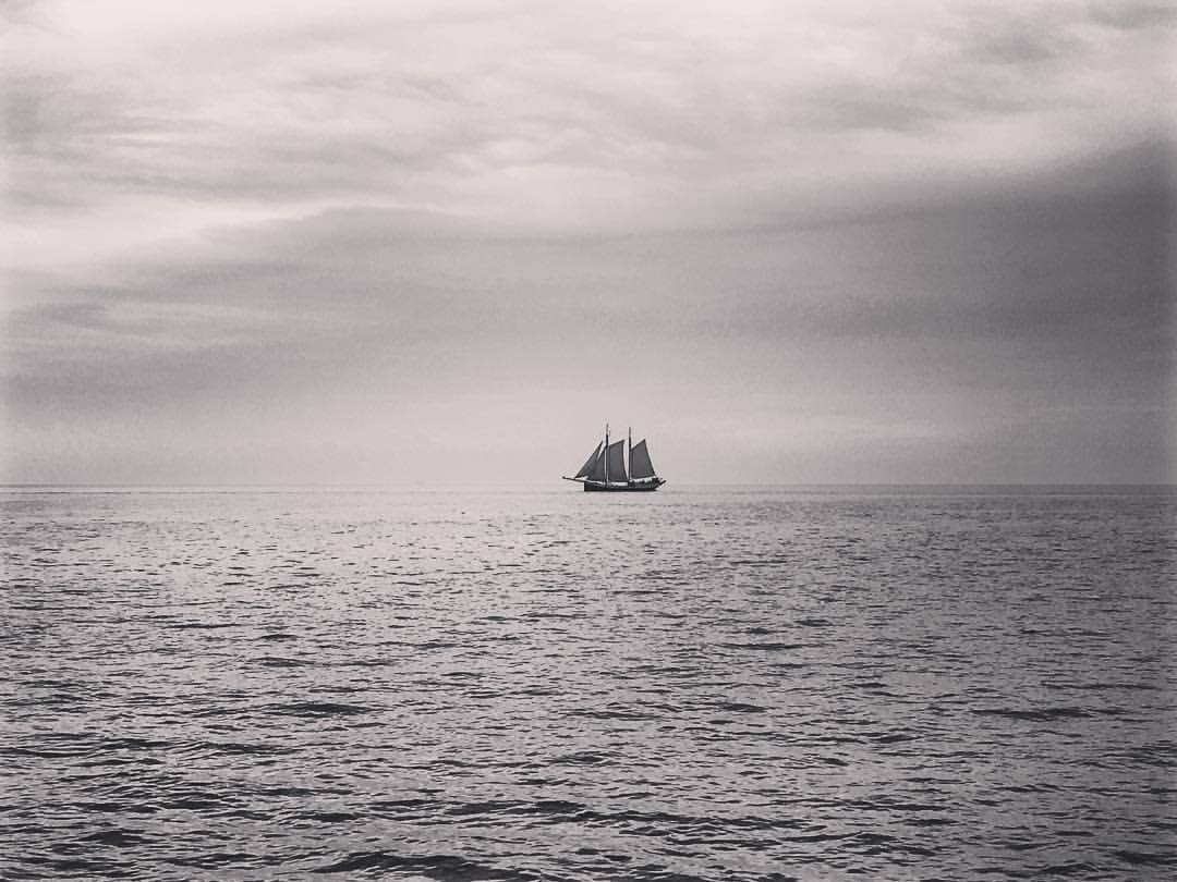Segelschiff auf ruhiger See unter bewölktem Himmel, Fernsicht.