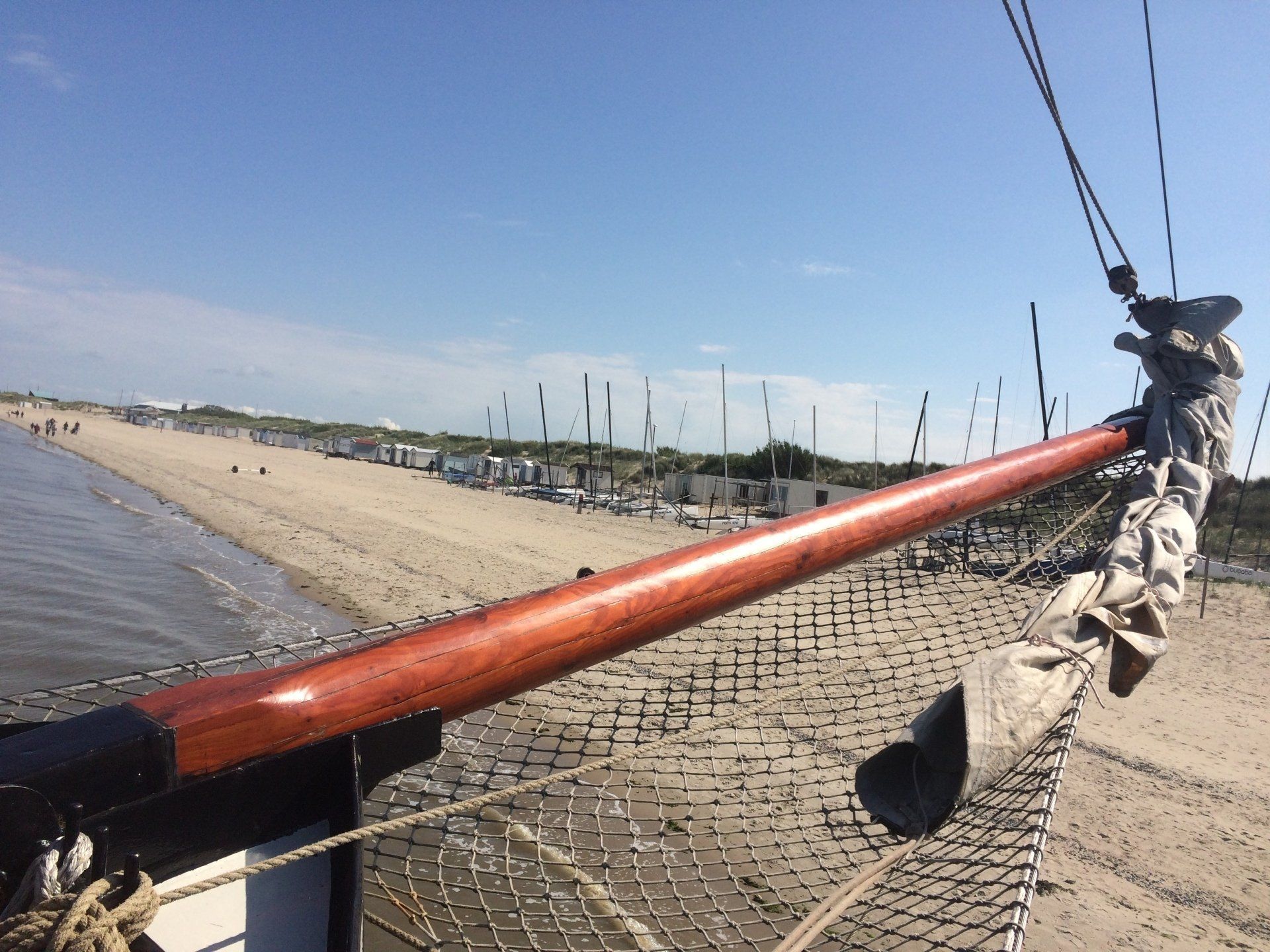 Der Bug eines Holzbootes zeigt an einem sonnigen Tag auf einen Sandstrand.