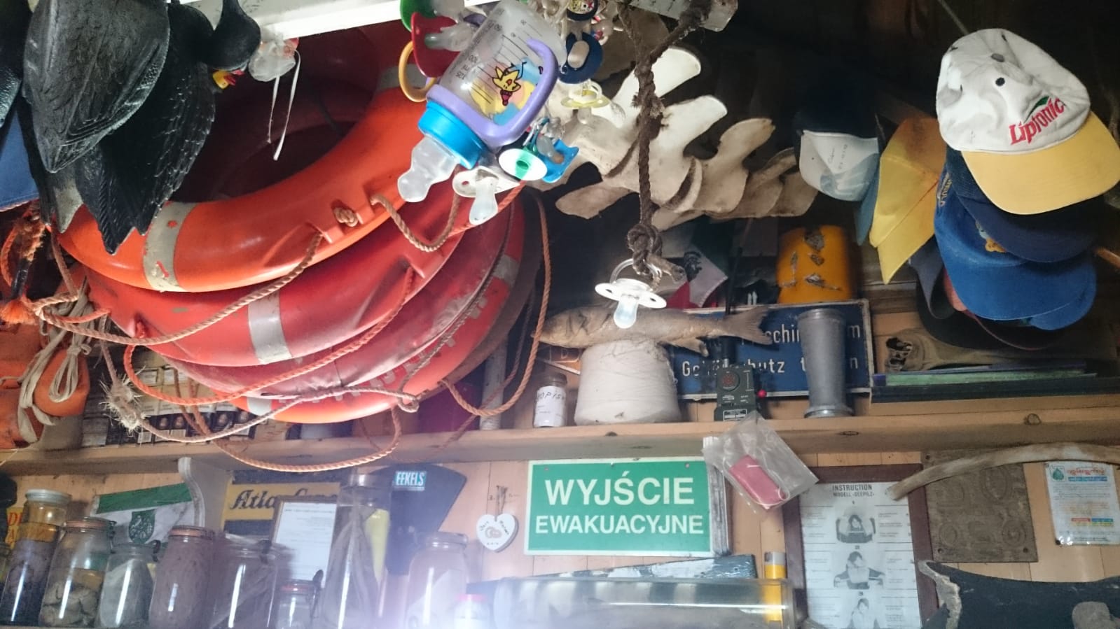 Ein überfülltes Regal mit Rettungsringen, Hüten, Schildern, Gläsern und verschiedenen Gegenständen.