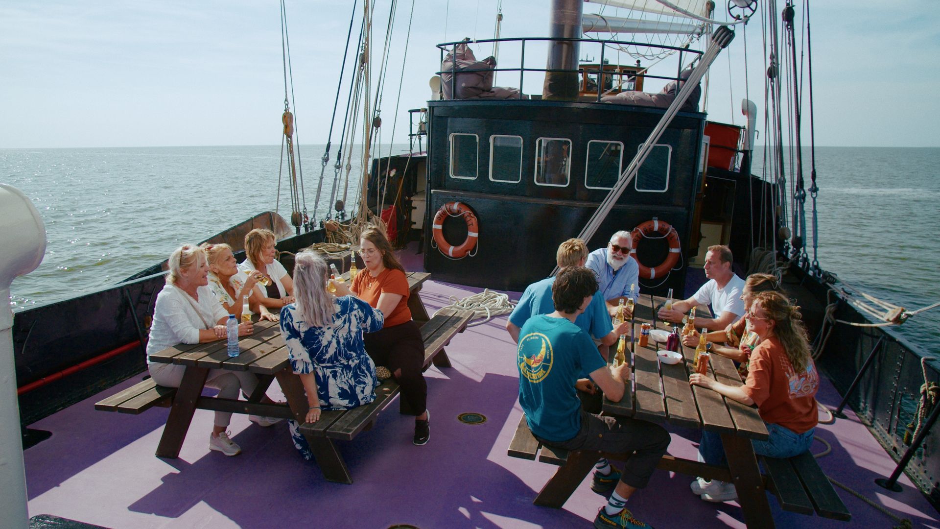 Gäste sitzen an den Tischen auf dem Deck der Storebælt beim Segeln über das Wattenmeer