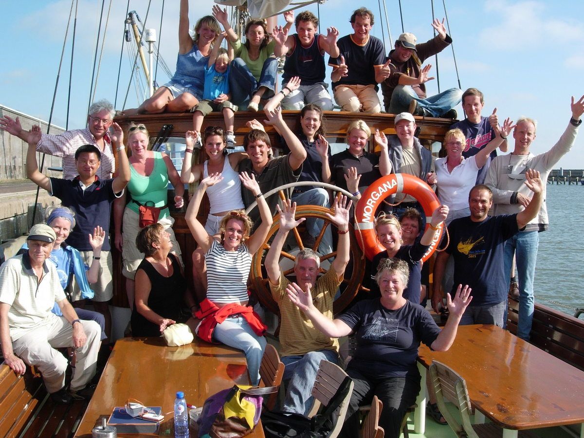 Gäste sitzen an den Tischen auf dem Deck der Storebælt beim Segeln über das Wattenmeer