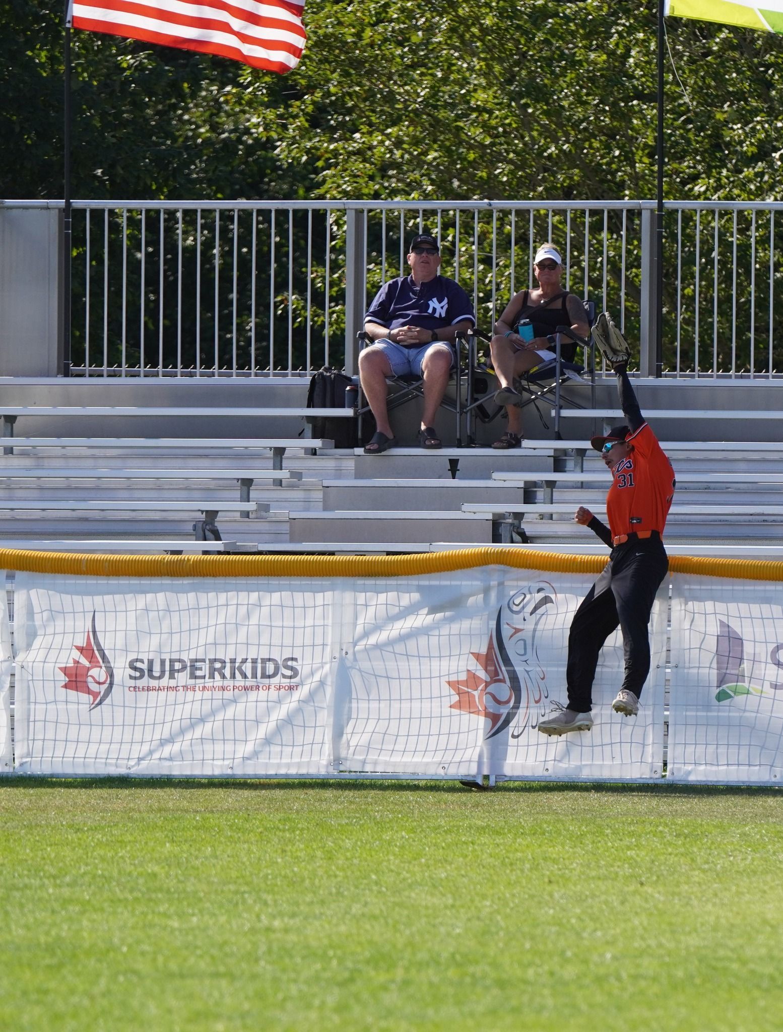 A Georgian Bay Giants outfielder leaps for a ball against the fence