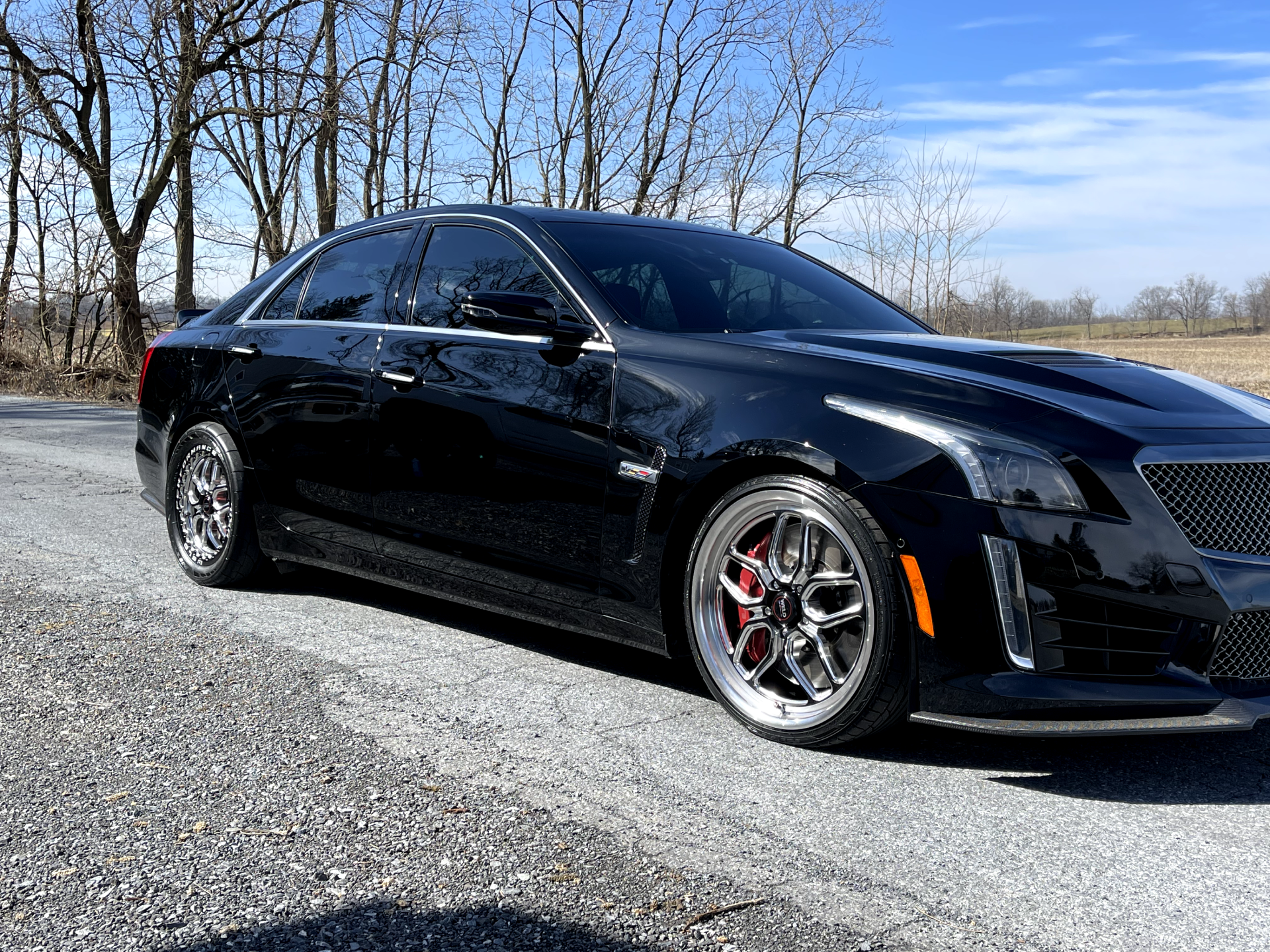 a black cadillac is parked on the side of the road .