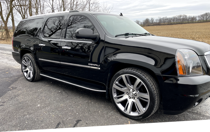 a black suv is parked on the side of the road .
