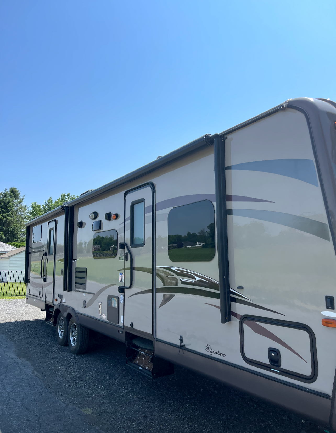 a rv is parked on the side of the road on a sunny day .
