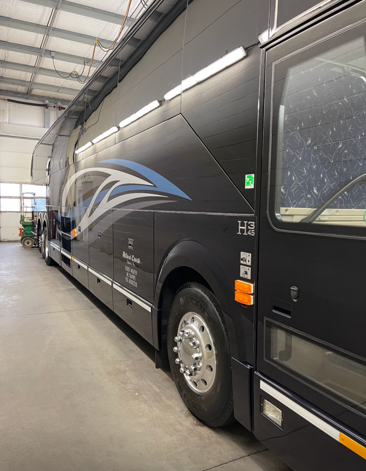a large black bus is parked in a garage