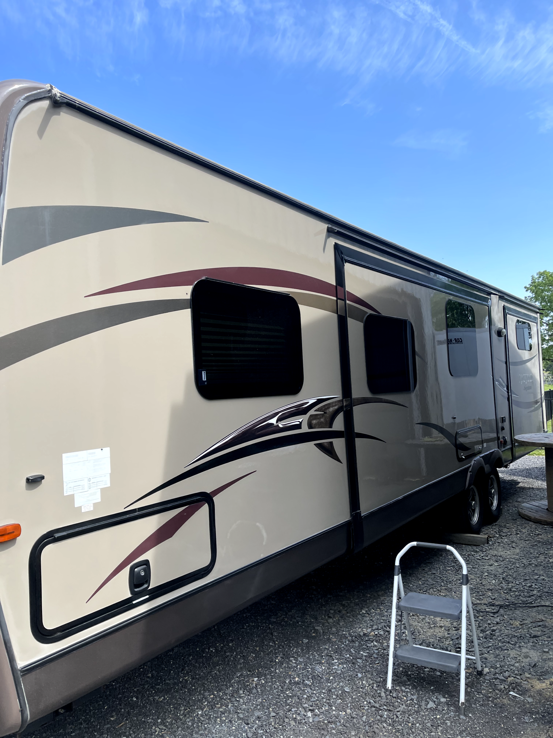 a rv is parked in a gravel lot next to a ladder