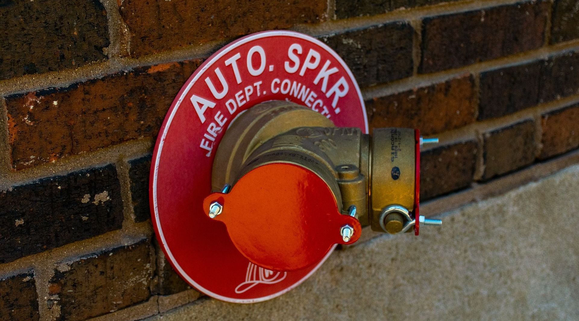 A red sign on a brick wall says auto spkr fire dept connect