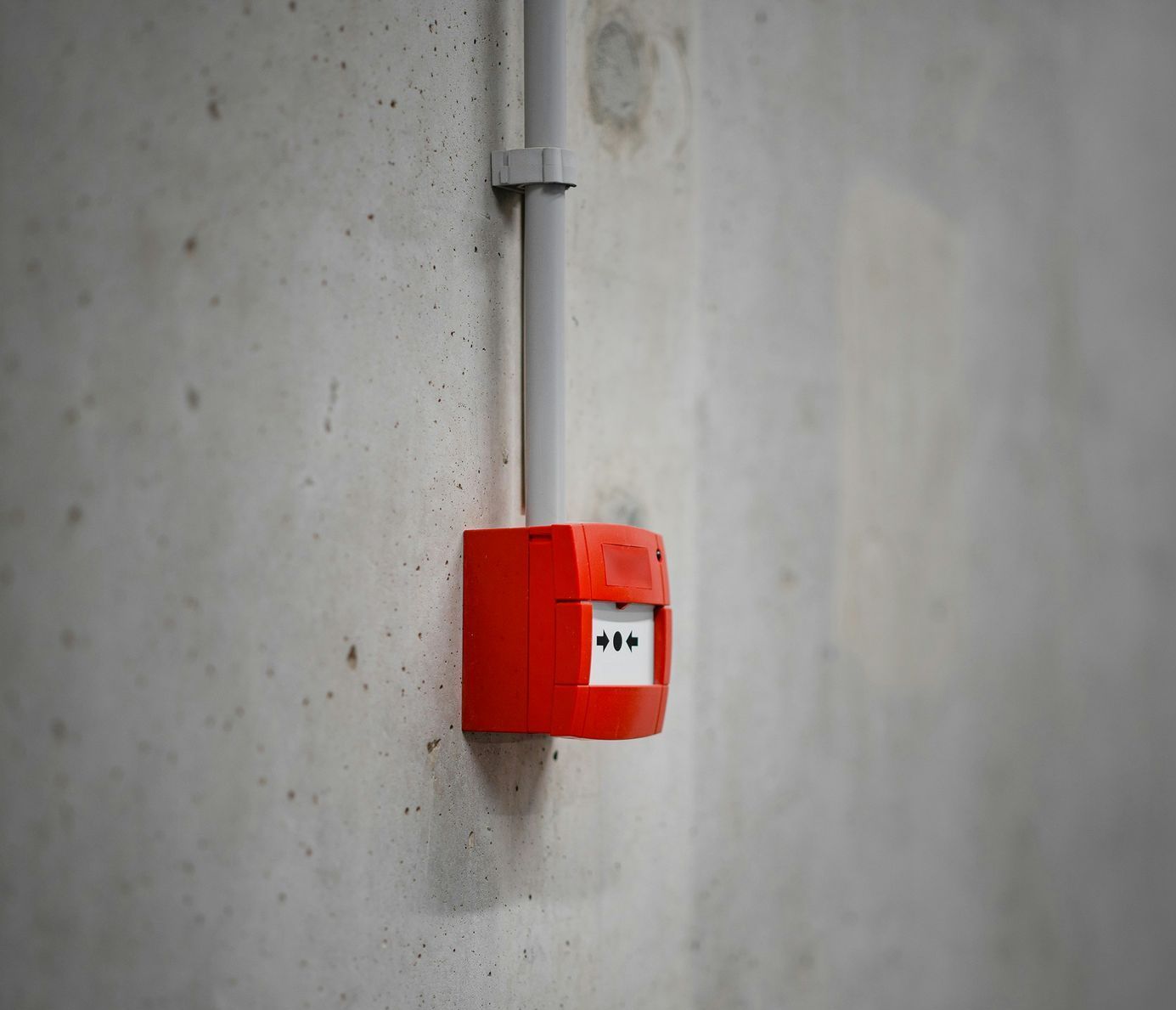 A red fire alarm is mounted on a concrete wall.