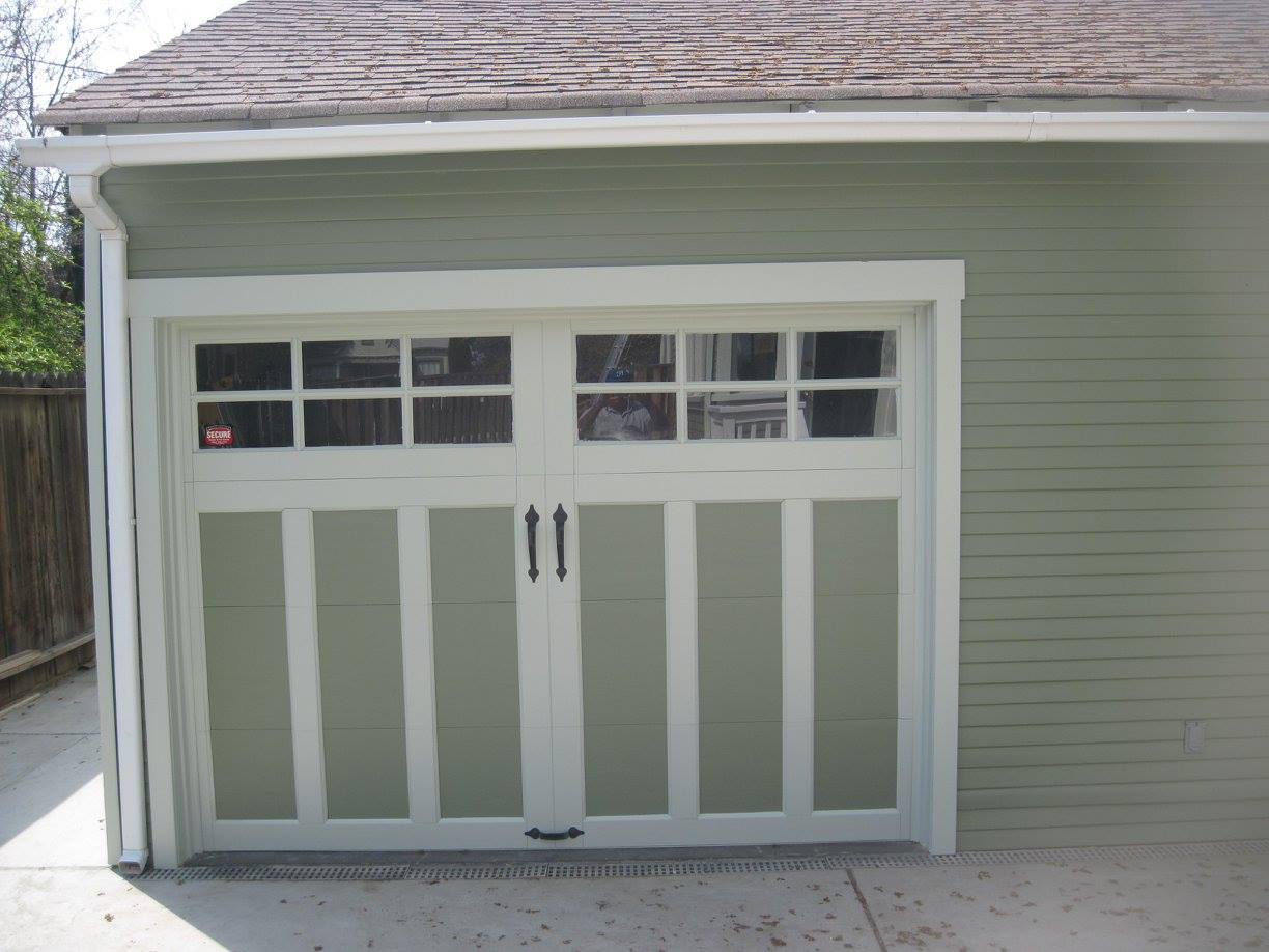 A green garage with a white door and windows