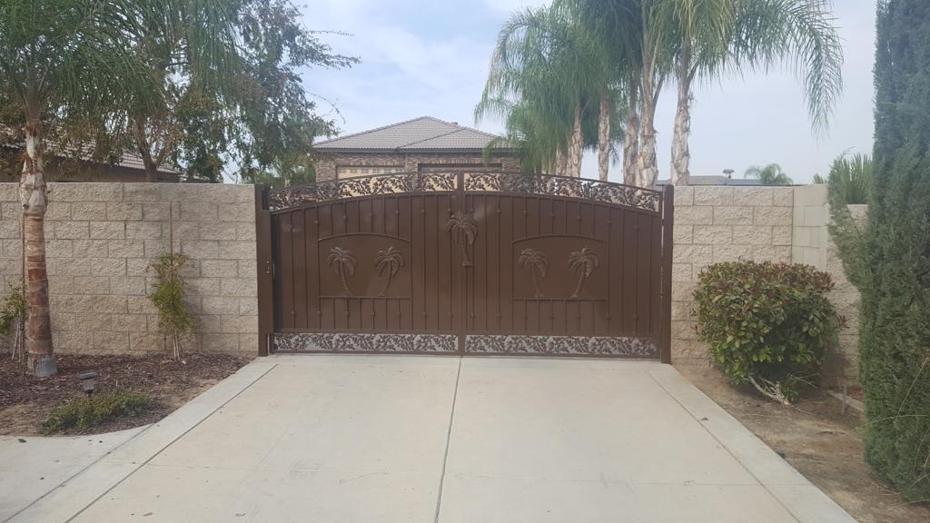 There is a large gate in the middle of a driveway leading to a house.