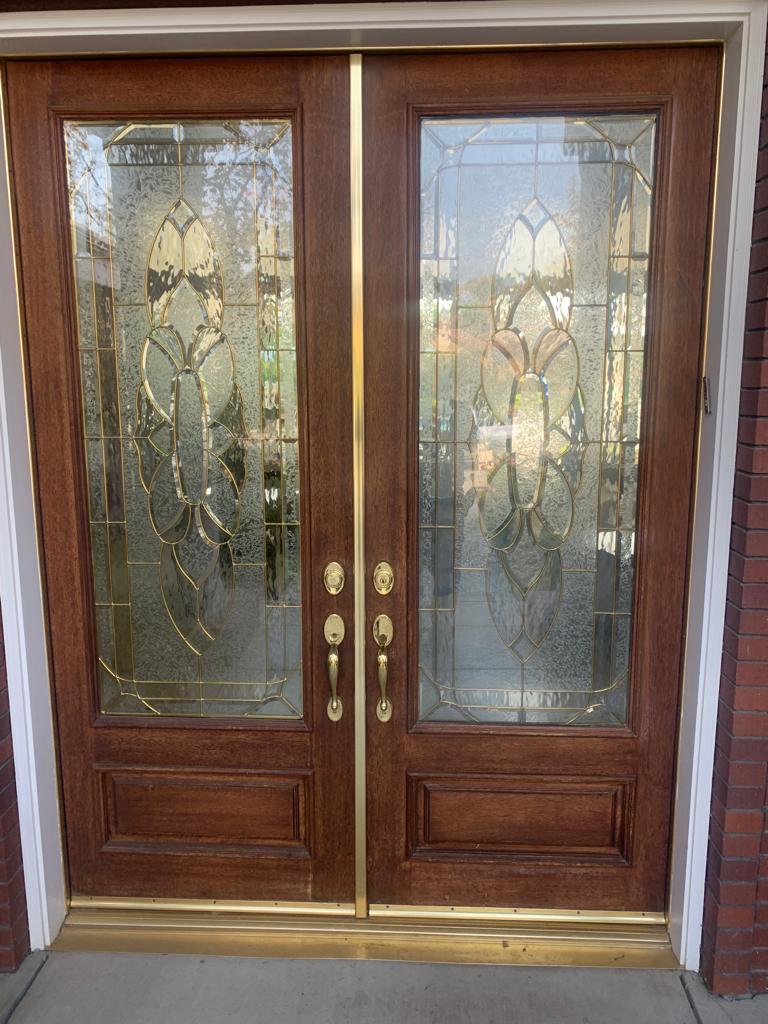 A pair of wooden doors with stained glass windows on a brick building.