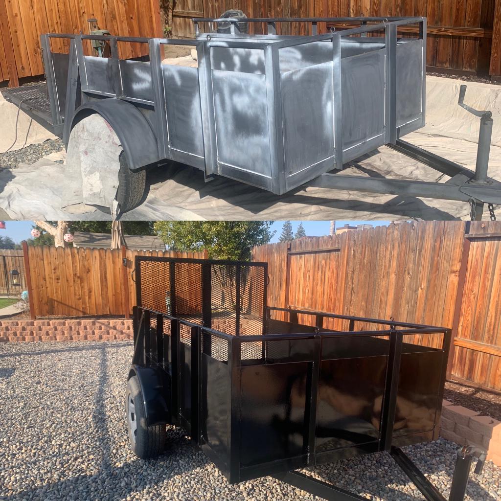 A trailer is sitting in front of a wooden fence.