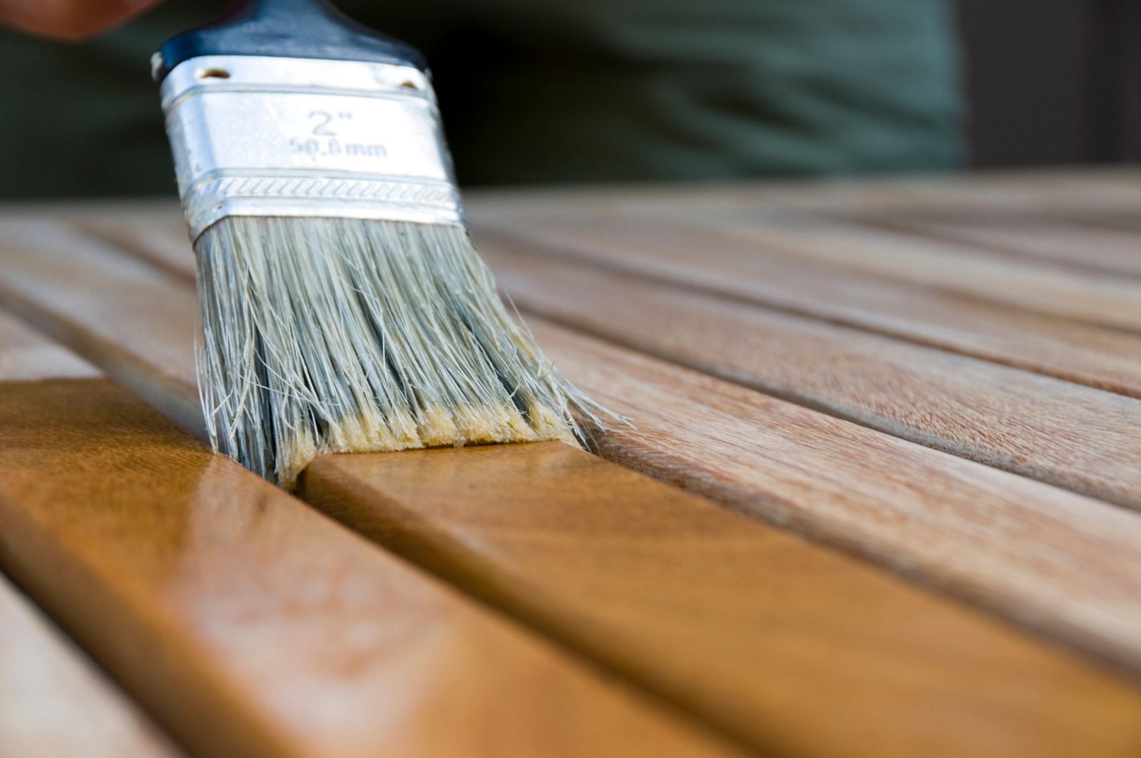 A person is painting a wooden table with a brush.