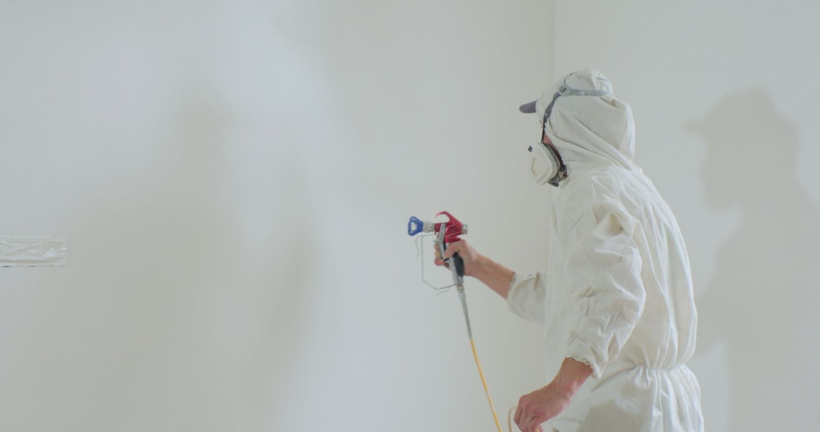 A man in a protective suit is spray painting a wall.