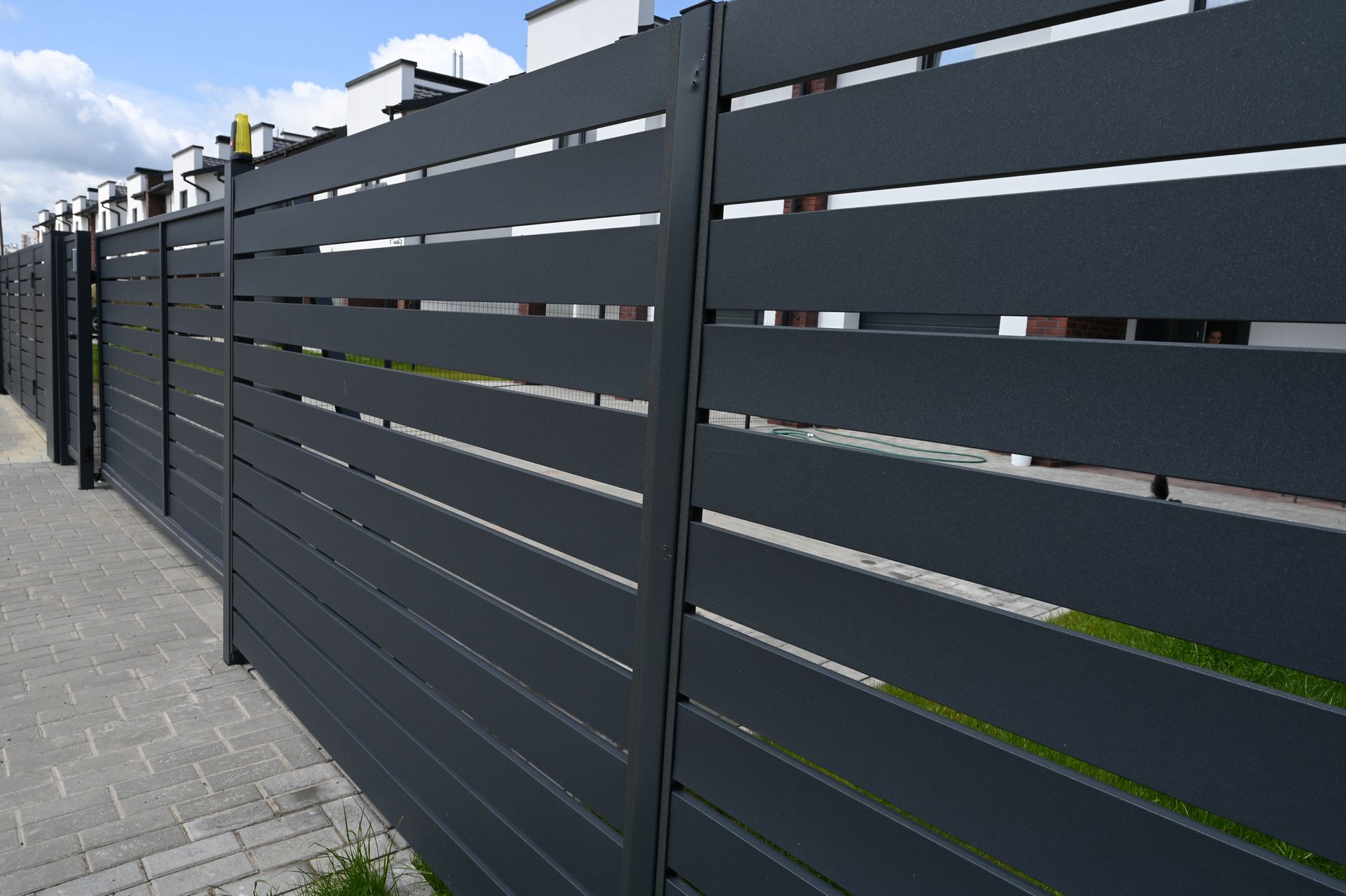 High grey fencing, made with aluminum slats.