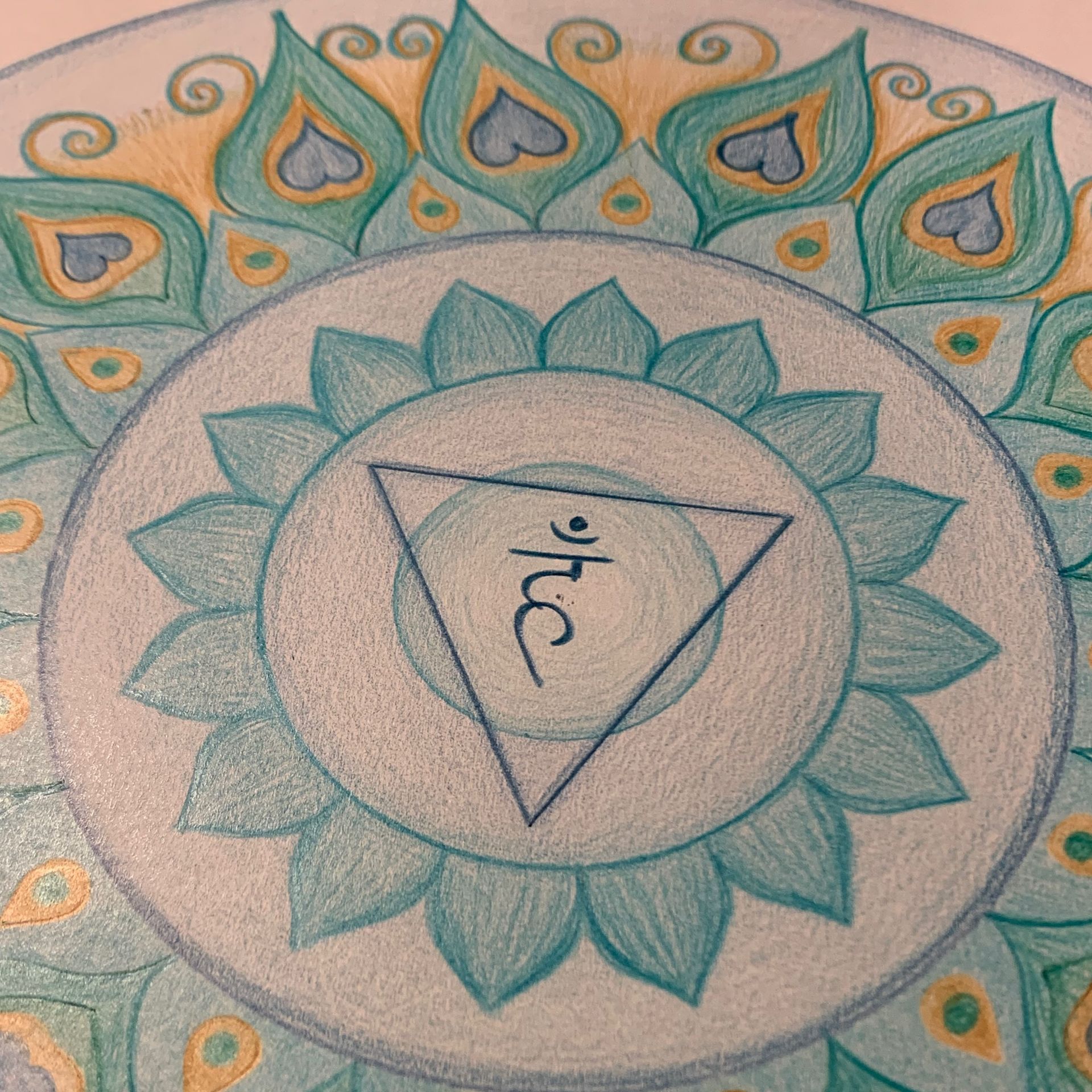 Teal and gold chakra mandala with a triangle containing a sanskrit symbol.