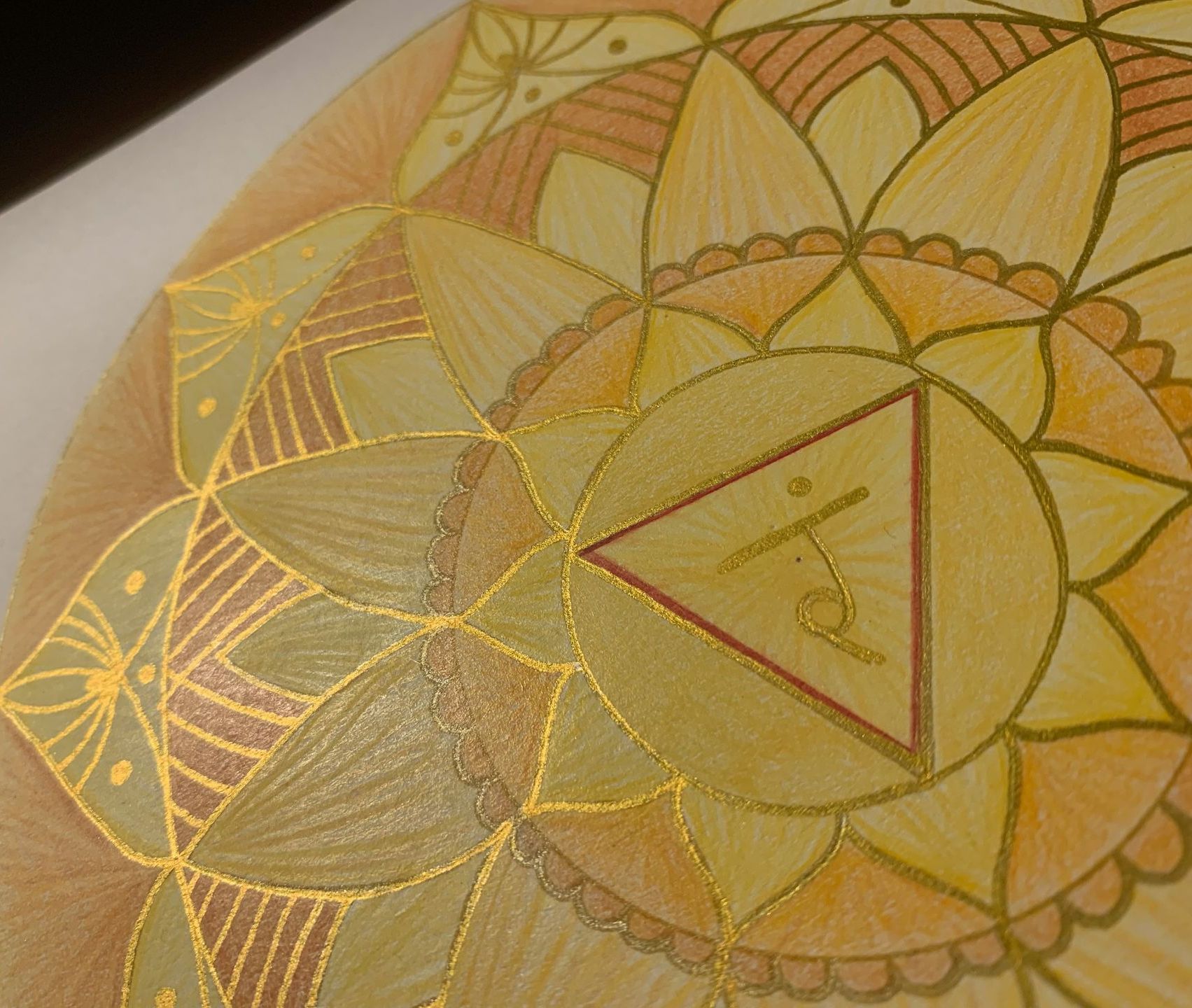 Golden mandala with intricate patterns and a central triangle symbol.
